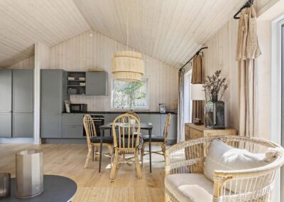 Køkken-alrum i sommerhus med træpaneler, gråt køkken, spiseplads og udgang til terrasse, fotograferet i Odsherred