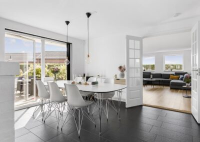 Spisestue med hvidt spisebord, formstøbte stole og store skydedøre mod terrasse, fotograferet til professionel boligmarkedsføring i Vestsjælland