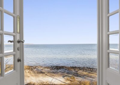 Havudsigt fra sommerhus gennem franske døre med kig til strand og vand, fotograferet til præsentation af kystnær fritidsbolig i Danmark